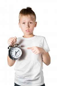 Young Boy Showing Alarm Clock, Isolated on White
