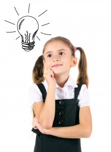 Beautiful little girl in school uniform with idea bulb above the head, isolated on white
